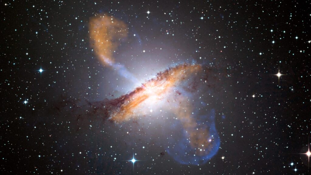 Galaxia vista de canto sobre fondo estrellado. Grandes chorros de gas salen hacia arriba y hacia abajo de la galaxia.