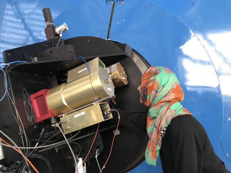 La doctora Alam observando de cerca el mecanismo de un telescopio. 